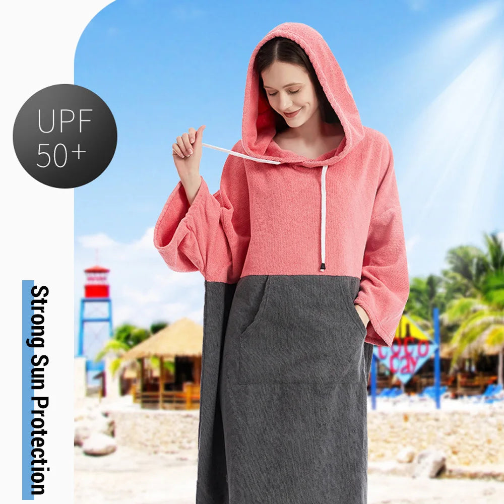 Woman wearing a pink and gray hooded towel poncho, designed for sun protection at the beach, featuring UPF 50+ rating.