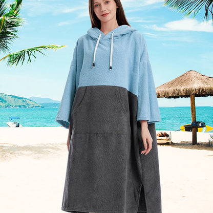 Young woman wearing a quick-dry hooded towel poncho on a sandy beach, perfect for surfing and swimming adventures.