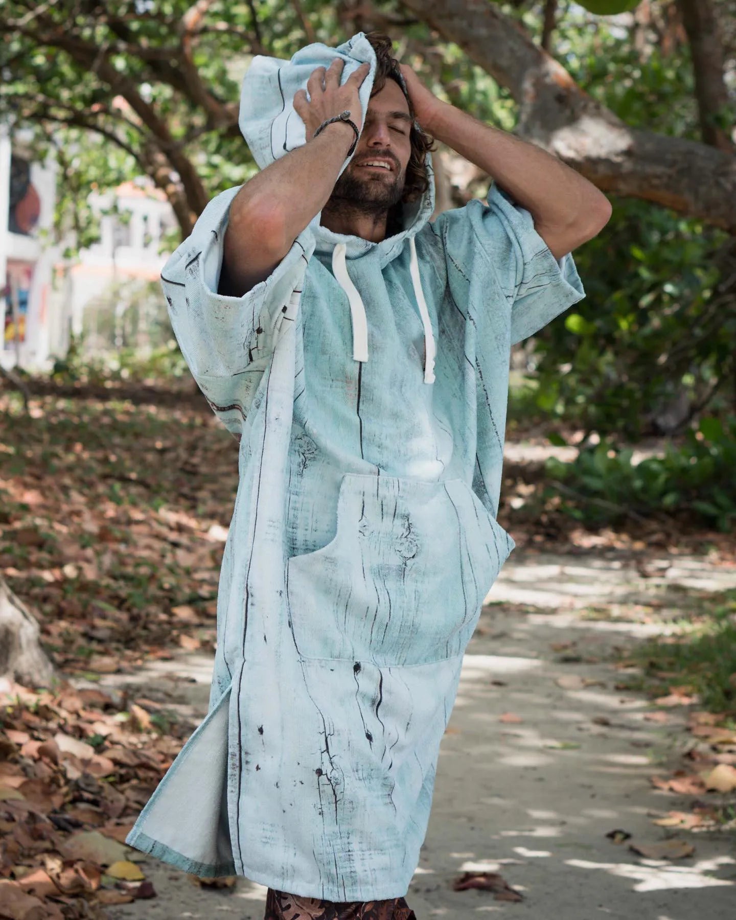 Man wearing a swimming diving hooded bathrobe poncho in a natural outdoor setting.