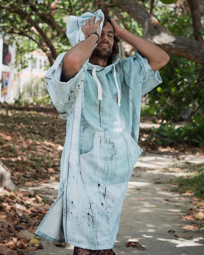 Man wearing a swimming diving hooded bathrobe poncho in a natural outdoor setting.