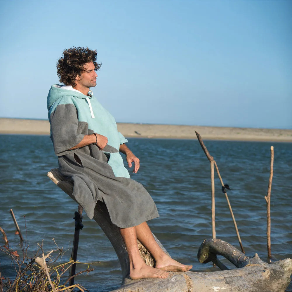 Man wearing a thicken hooded bathrobe poncho by the water, enjoying warmth and comfort after swimming or diving.